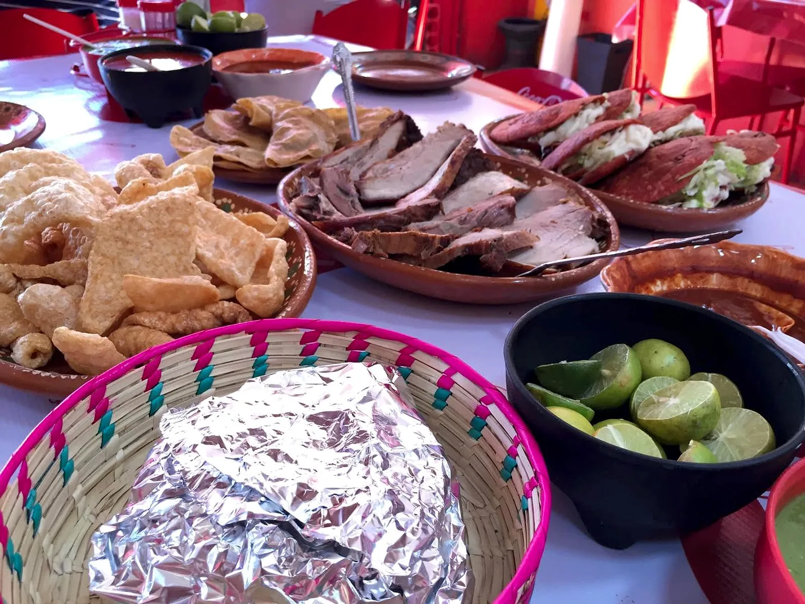Mesa servida con carnitas, duritos, tortas, limones y salsas