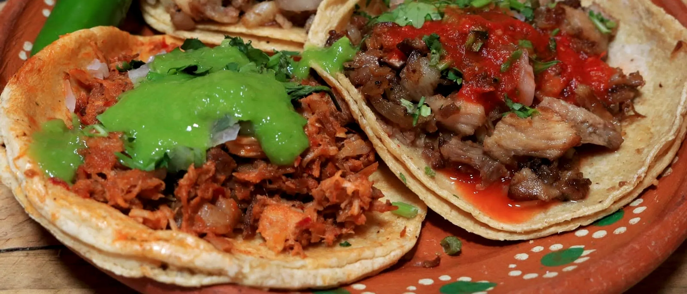 Tacos de carnitas servidos en plato de barro con salsa y limón
