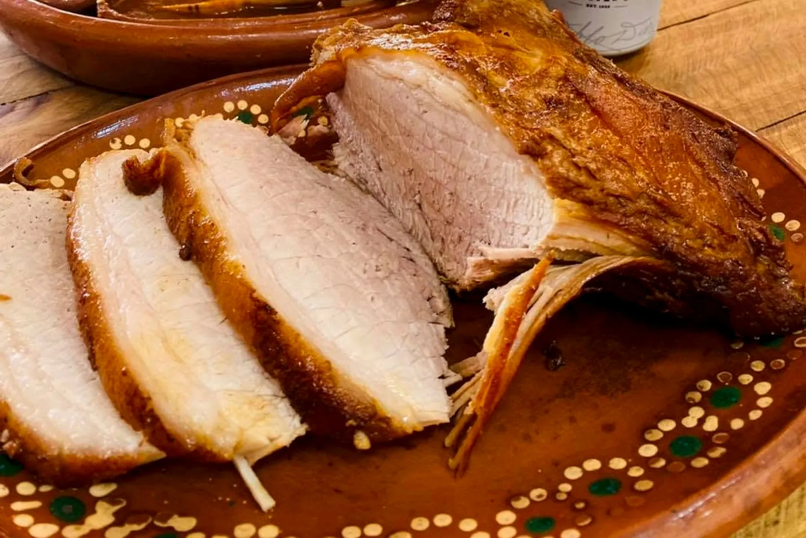 Chamorro rebanado servido en plato de barro sobre la mesa del local