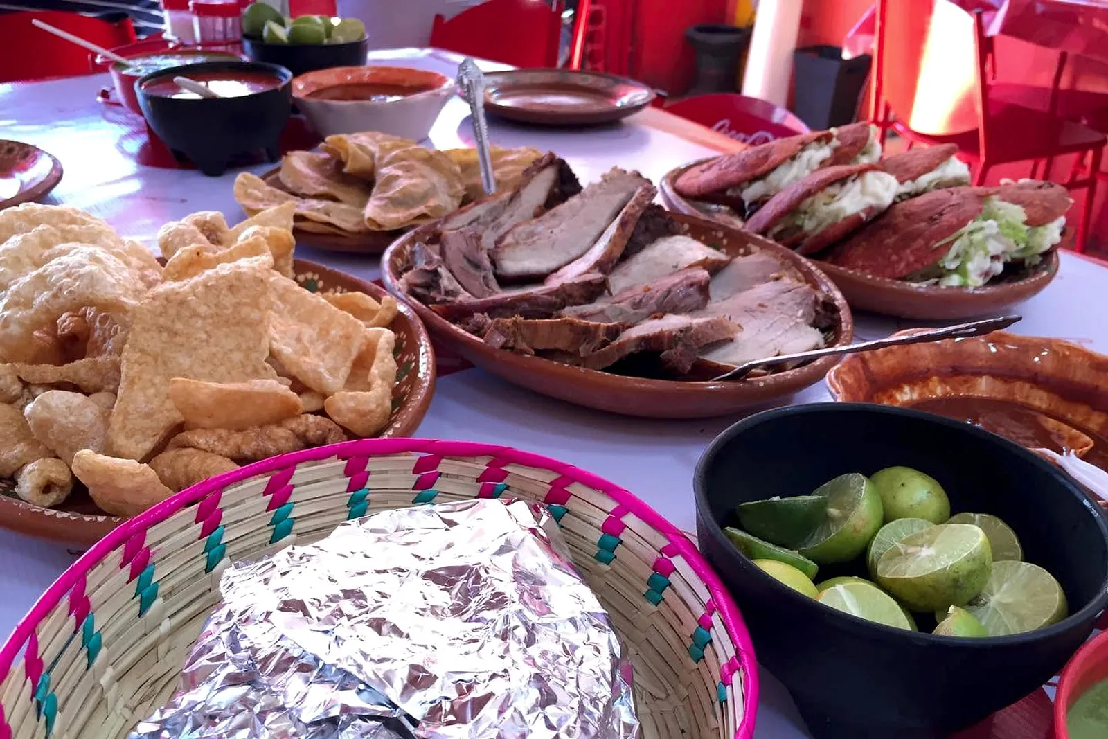 Mesa servida con carnitas, duritos, tortas, limones y salsas para compartir