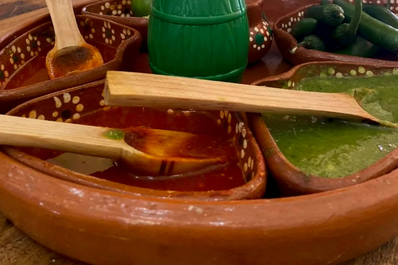 Salsero de barro con salsa roja y verde en la mesa del local